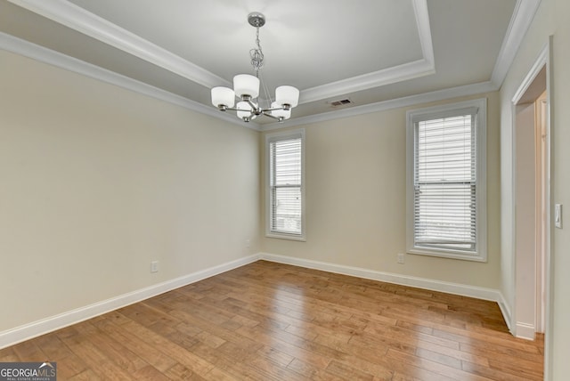 unfurnished room with ornamental molding, light hardwood / wood-style flooring, a chandelier, and a tray ceiling