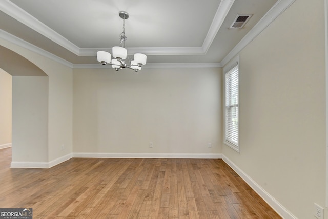 empty room featuring a wealth of natural light, an inviting chandelier, light wood-type flooring, and crown molding