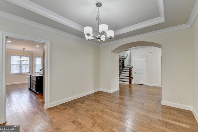 spare room with light hardwood / wood-style flooring, a notable chandelier, sink, and crown molding