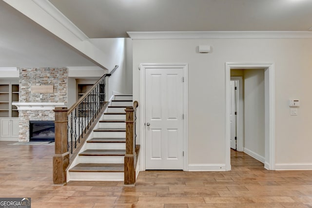 staircase featuring a fireplace, hardwood / wood-style floors, and crown molding