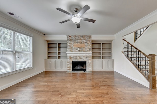 unfurnished living room featuring a fireplace, ceiling fan, crown molding, and light hardwood / wood-style flooring