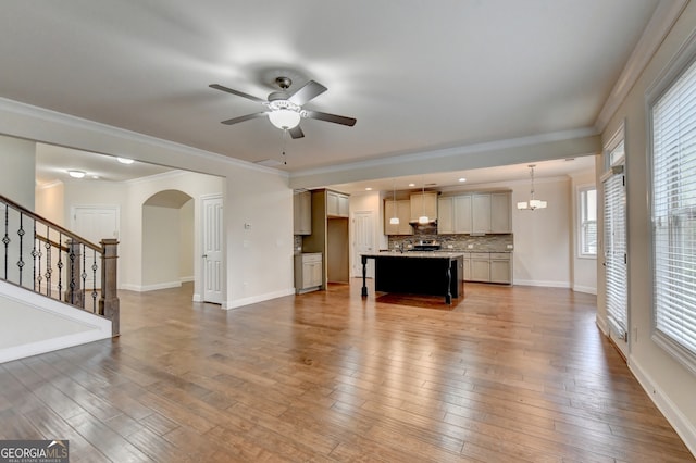 unfurnished living room with hardwood / wood-style flooring, ceiling fan with notable chandelier, and ornamental molding