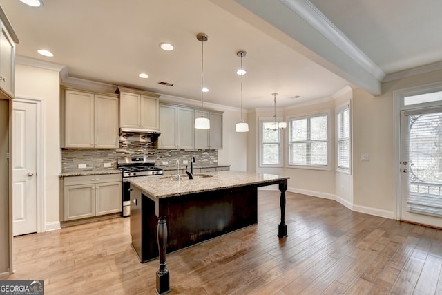 kitchen featuring light stone counters, decorative light fixtures, light hardwood / wood-style floors, a breakfast bar area, and gas range