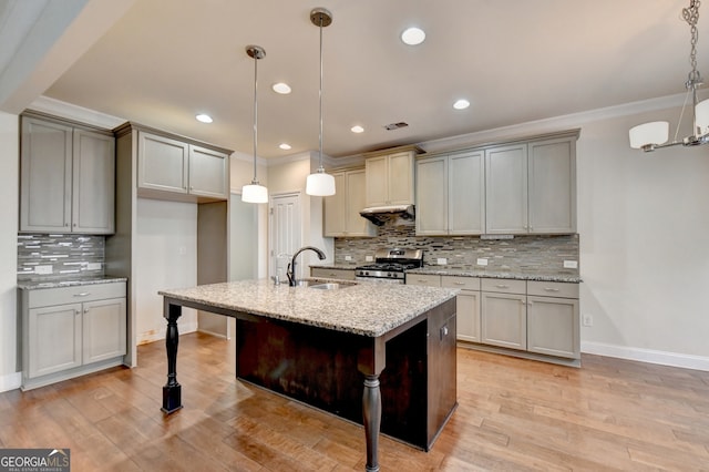 kitchen featuring stainless steel gas range oven, sink, pendant lighting, and light hardwood / wood-style flooring