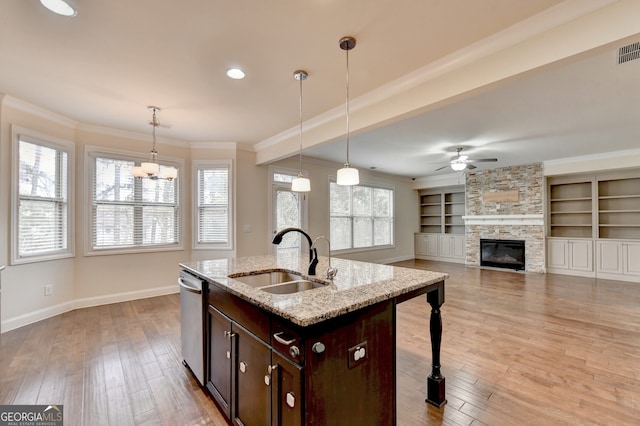 kitchen with pendant lighting, sink, dark brown cabinets, and light wood-type flooring