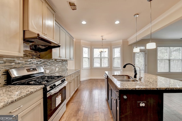 kitchen with gas range, pendant lighting, sink, light hardwood / wood-style floors, and cream cabinetry