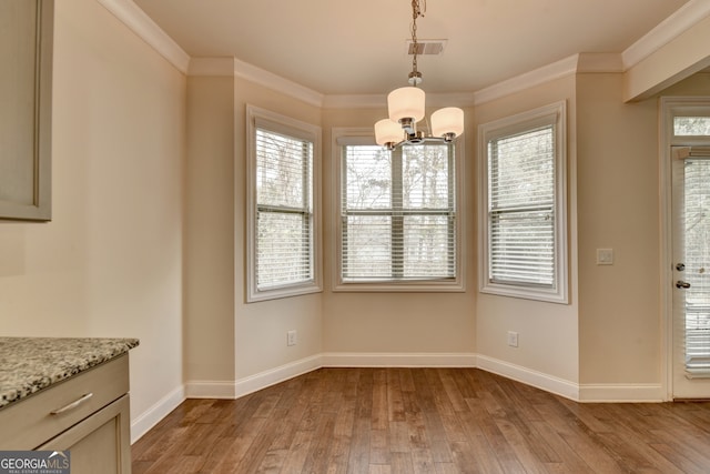 unfurnished dining area featuring light wood-type flooring, ornamental molding, and plenty of natural light