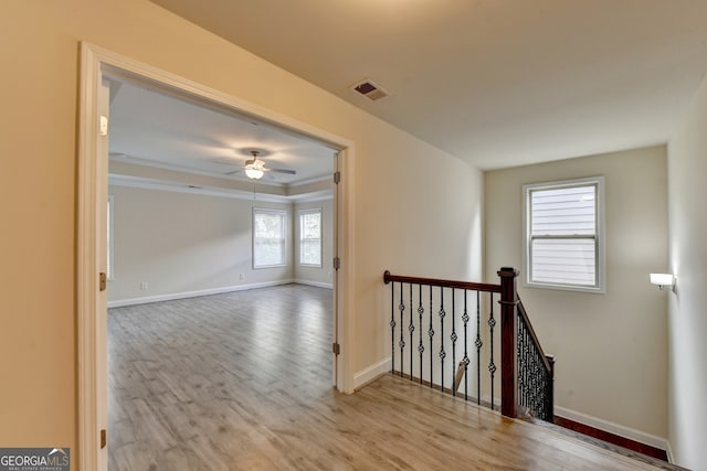 corridor with ornamental molding and light hardwood / wood-style flooring