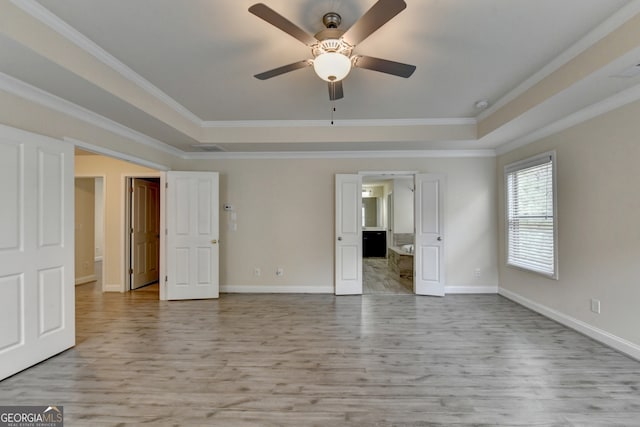 interior space with ceiling fan, a tray ceiling, ornamental molding, and light hardwood / wood-style flooring