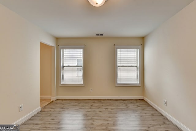 empty room with a wealth of natural light and light hardwood / wood-style floors