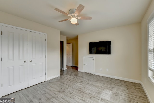 unfurnished bedroom with ceiling fan, a closet, and light wood-type flooring