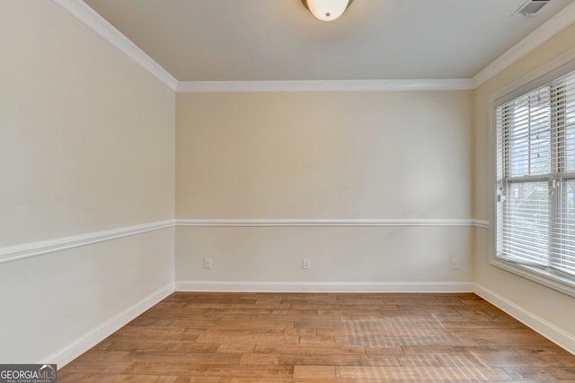 spare room featuring ornamental molding and light hardwood / wood-style floors