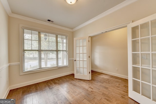 unfurnished room featuring crown molding, light wood-type flooring, and french doors