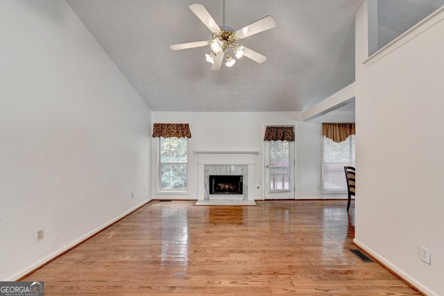 unfurnished living room featuring a wealth of natural light, ceiling fan, and light hardwood / wood-style flooring