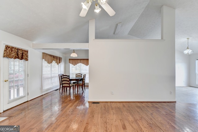 interior space featuring hardwood / wood-style flooring, ceiling fan, a textured ceiling, and vaulted ceiling