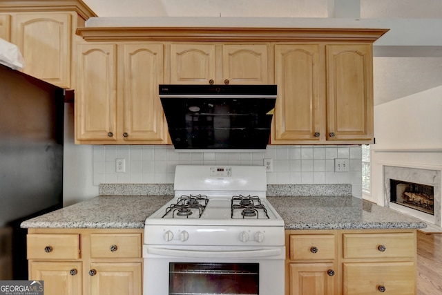 kitchen with exhaust hood, black appliances, light brown cabinetry, and backsplash