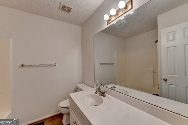 bathroom with toilet, hardwood / wood-style floors, a textured ceiling, vanity, and a shower