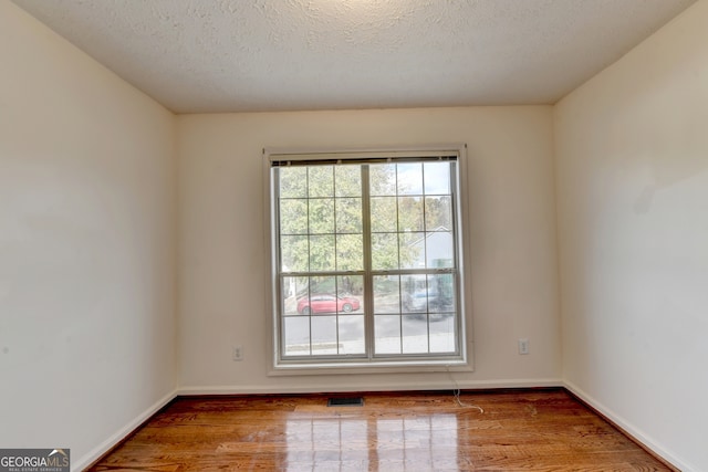 empty room with wood-type flooring and a textured ceiling