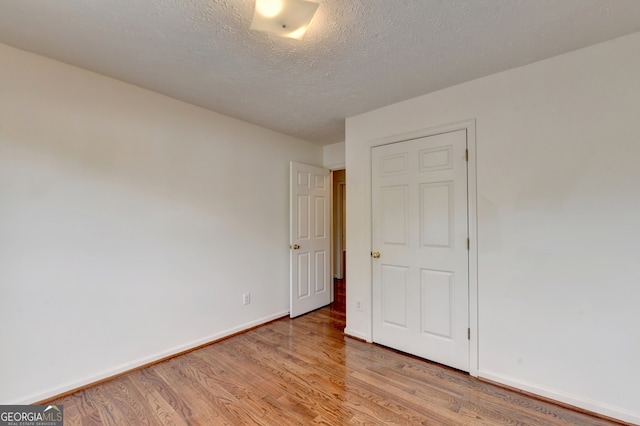 unfurnished bedroom with a textured ceiling and light hardwood / wood-style flooring