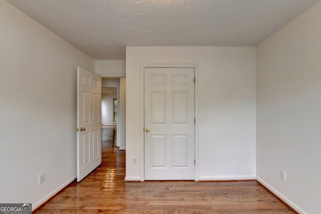 unfurnished bedroom with a textured ceiling and light wood-type flooring