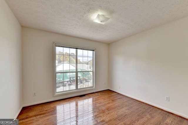 spare room with light wood-type flooring and a textured ceiling