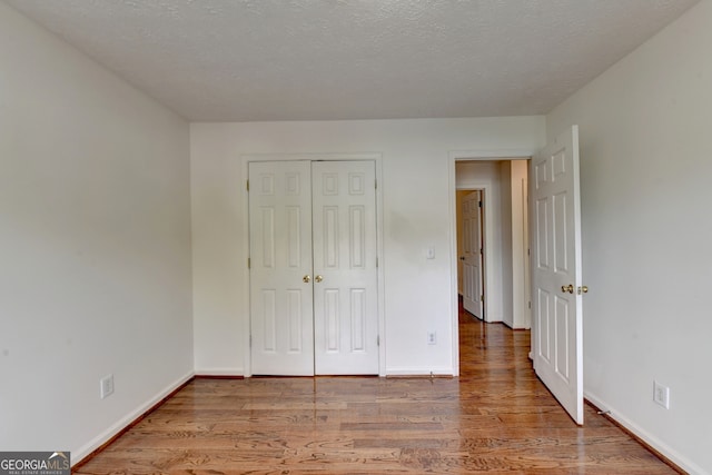 unfurnished bedroom with a closet, a textured ceiling, and light hardwood / wood-style flooring