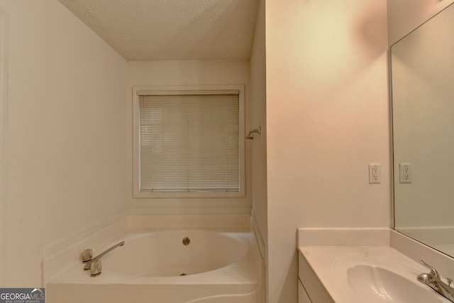 bathroom with a washtub, vanity, and a textured ceiling