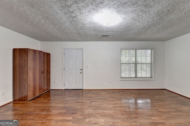 unfurnished room featuring a textured ceiling and hardwood / wood-style flooring