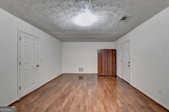 additional living space featuring a textured ceiling and light hardwood / wood-style flooring