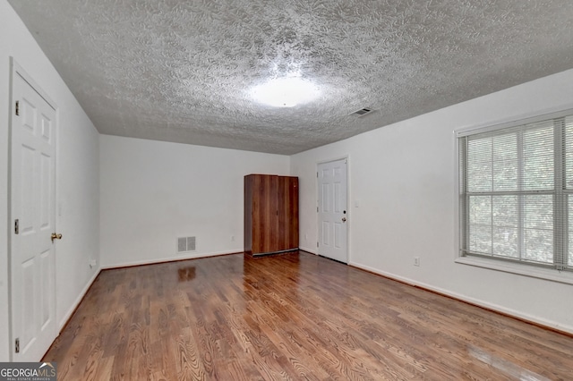 unfurnished room featuring hardwood / wood-style floors and a textured ceiling