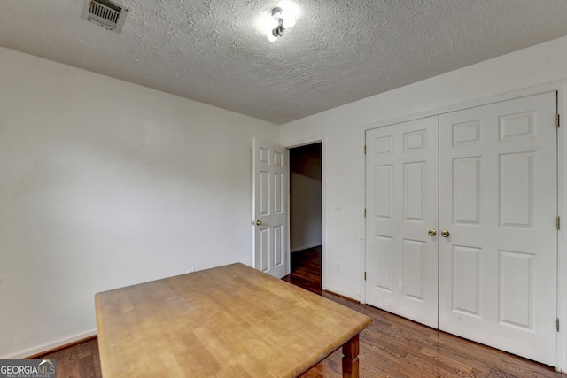 unfurnished office with dark hardwood / wood-style flooring and a textured ceiling