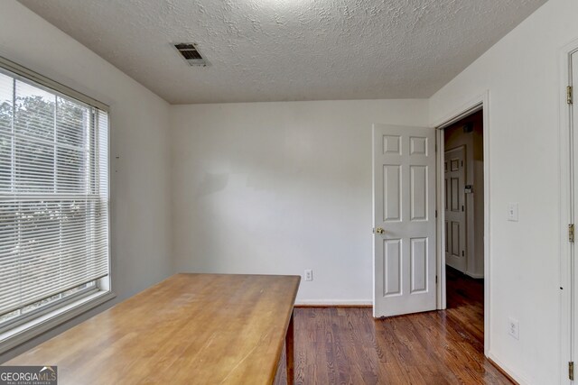 spare room featuring dark hardwood / wood-style flooring and a textured ceiling