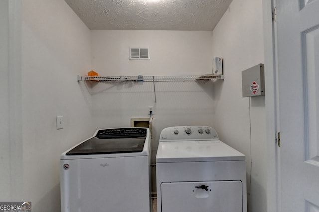 washroom featuring a textured ceiling and washer and dryer