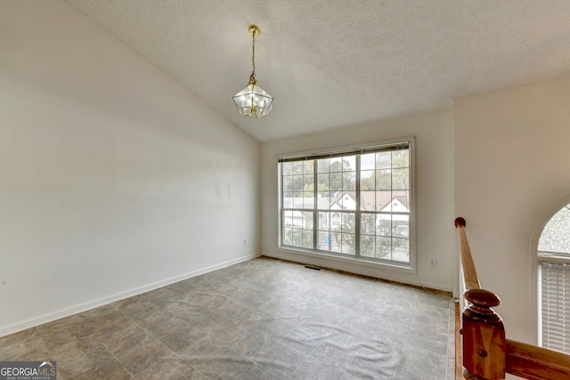 spare room with a textured ceiling, an inviting chandelier, and lofted ceiling