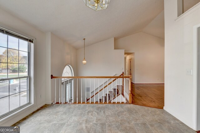 spare room featuring hardwood / wood-style floors, a chandelier, and vaulted ceiling