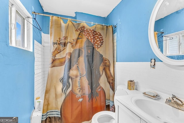 bathroom featuring toilet, vanity, curtained shower, and tile walls