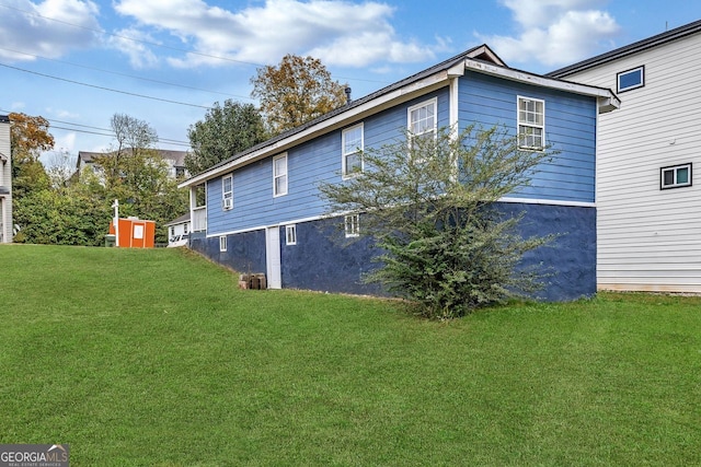 view of side of property with a lawn and a shed