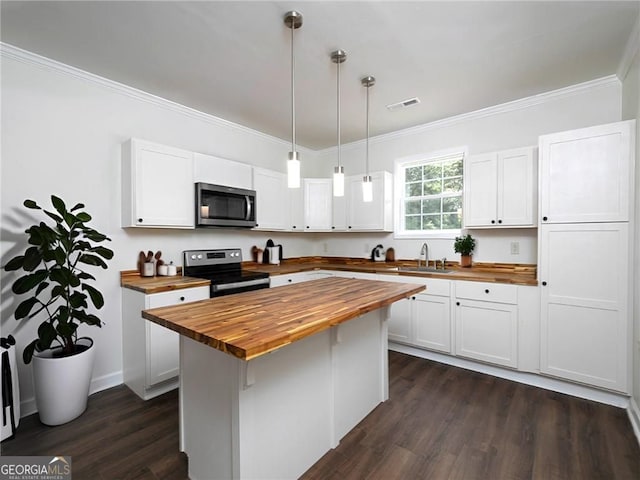 kitchen featuring white cabinets, black / electric stove, hanging light fixtures, and wood counters