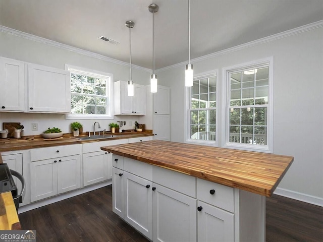 kitchen with pendant lighting, dark hardwood / wood-style floors, white cabinets, and butcher block countertops