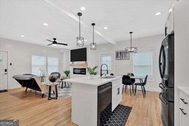 kitchen with a center island with sink, white cabinetry, sink, and pendant lighting