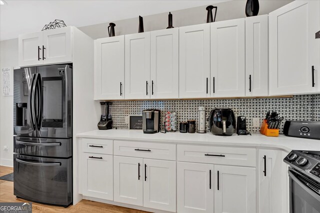 kitchen featuring white cabinets, light wood-type flooring, appliances with stainless steel finishes, and tasteful backsplash