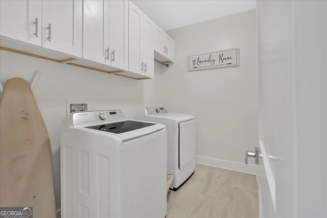 washroom with cabinets, washing machine and clothes dryer, and light tile patterned floors