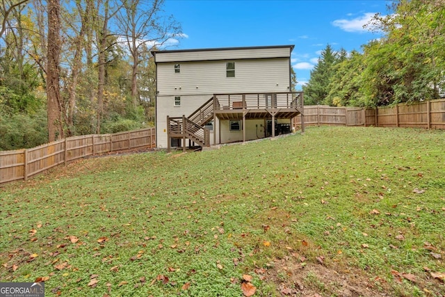 rear view of house featuring a wooden deck and a lawn