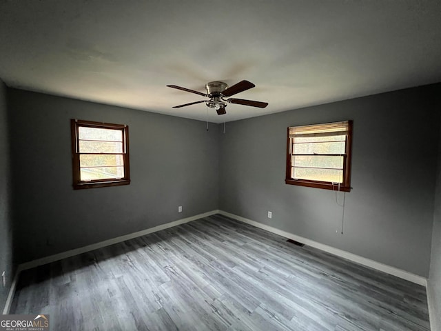 spare room featuring hardwood / wood-style floors, ceiling fan, and a healthy amount of sunlight