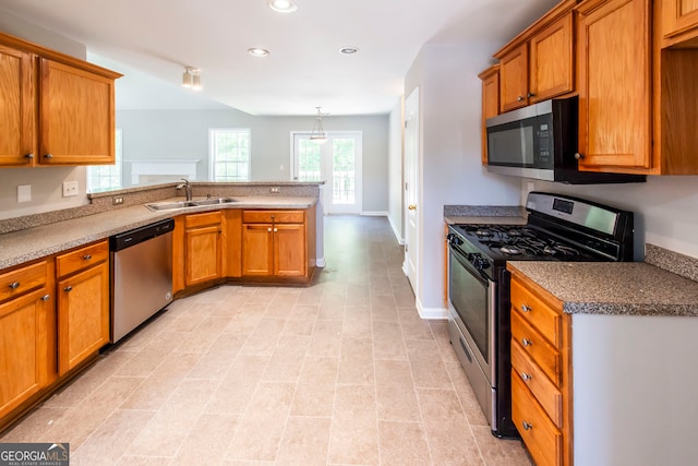 kitchen with pendant lighting, kitchen peninsula, appliances with stainless steel finishes, and sink