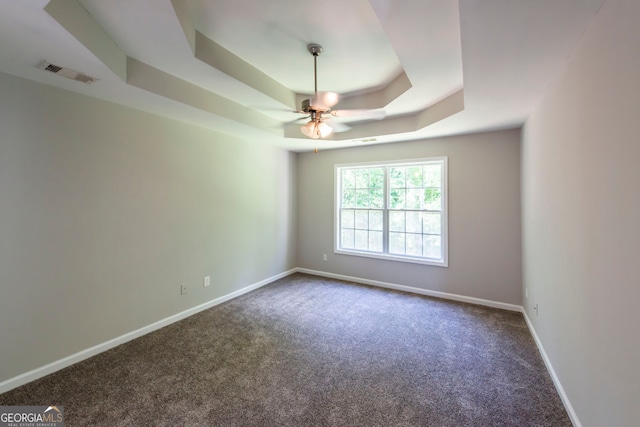 carpeted empty room with a tray ceiling and ceiling fan