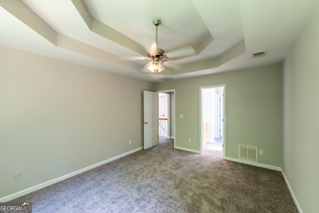 unfurnished bedroom featuring ceiling fan, a raised ceiling, and carpet