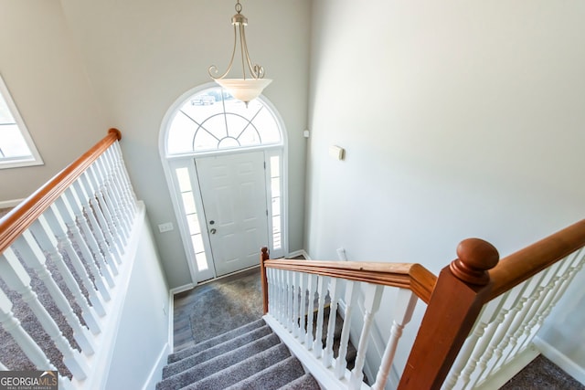 foyer entrance with dark carpet and a towering ceiling