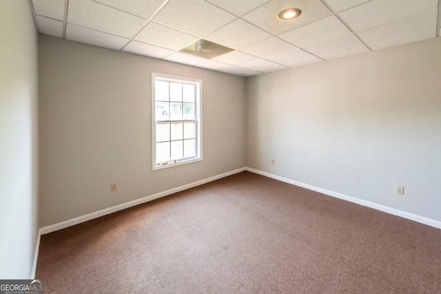 carpeted spare room featuring a drop ceiling