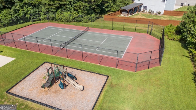 view of tennis court featuring a playground and a lawn